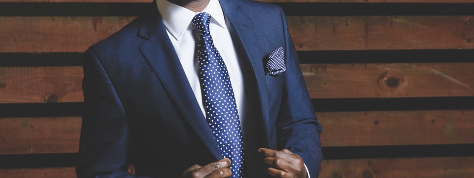 homme portant un costume bleu marine avec une cravate bleu marine et une chemise blanche