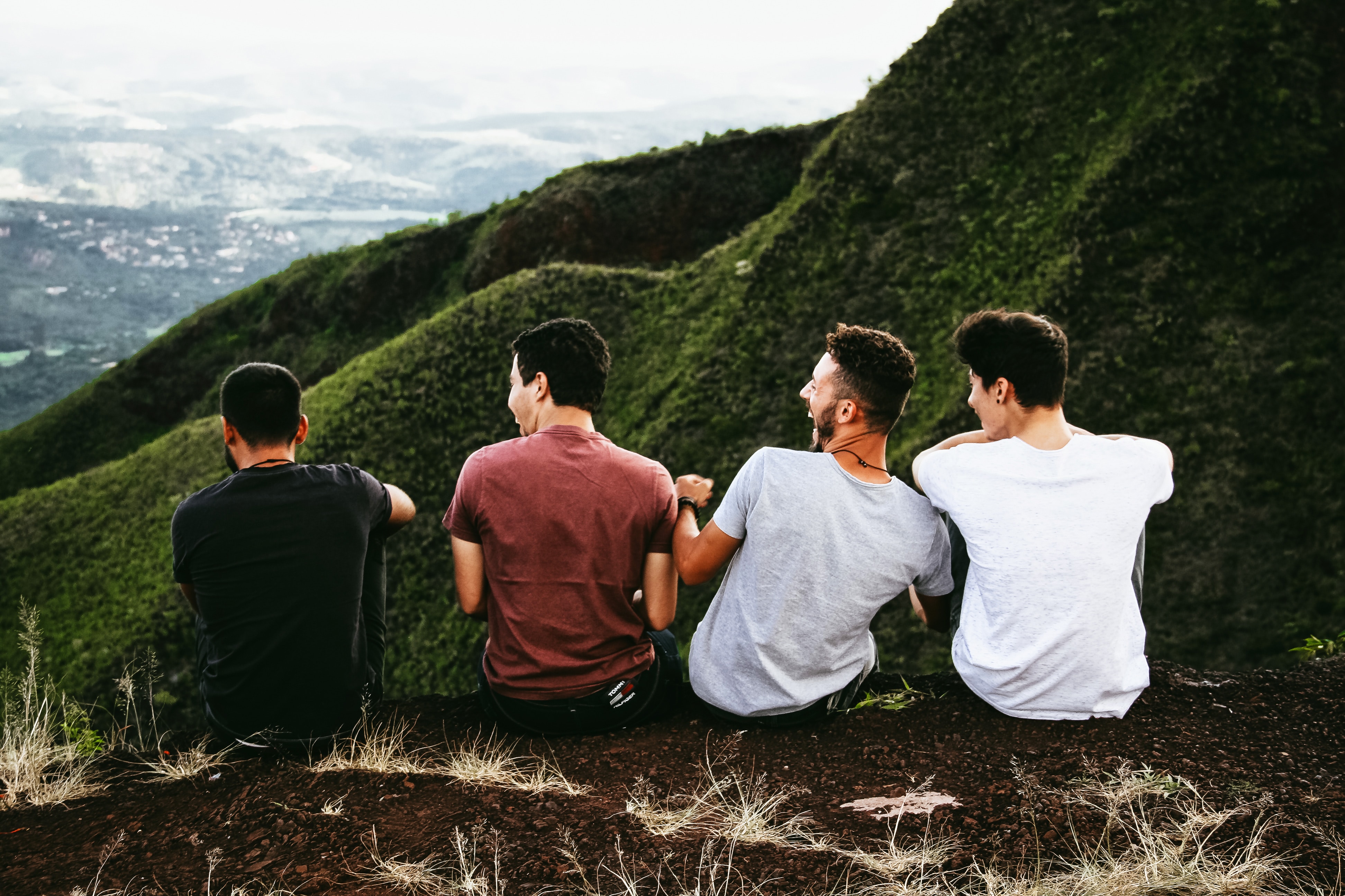 4 jeunes hommes riant ensemble assis sur le haut d'une montagne