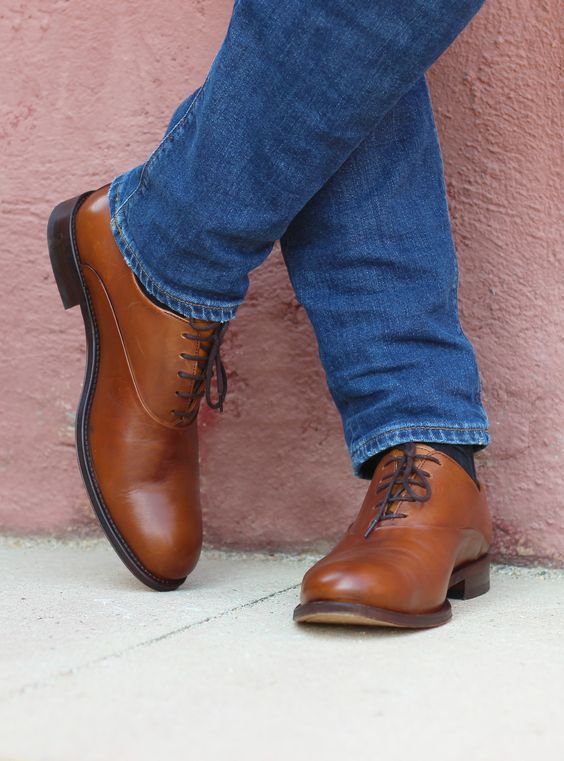 vue sur les pieds d'une homme portant un jean bleu et des richelieu marron