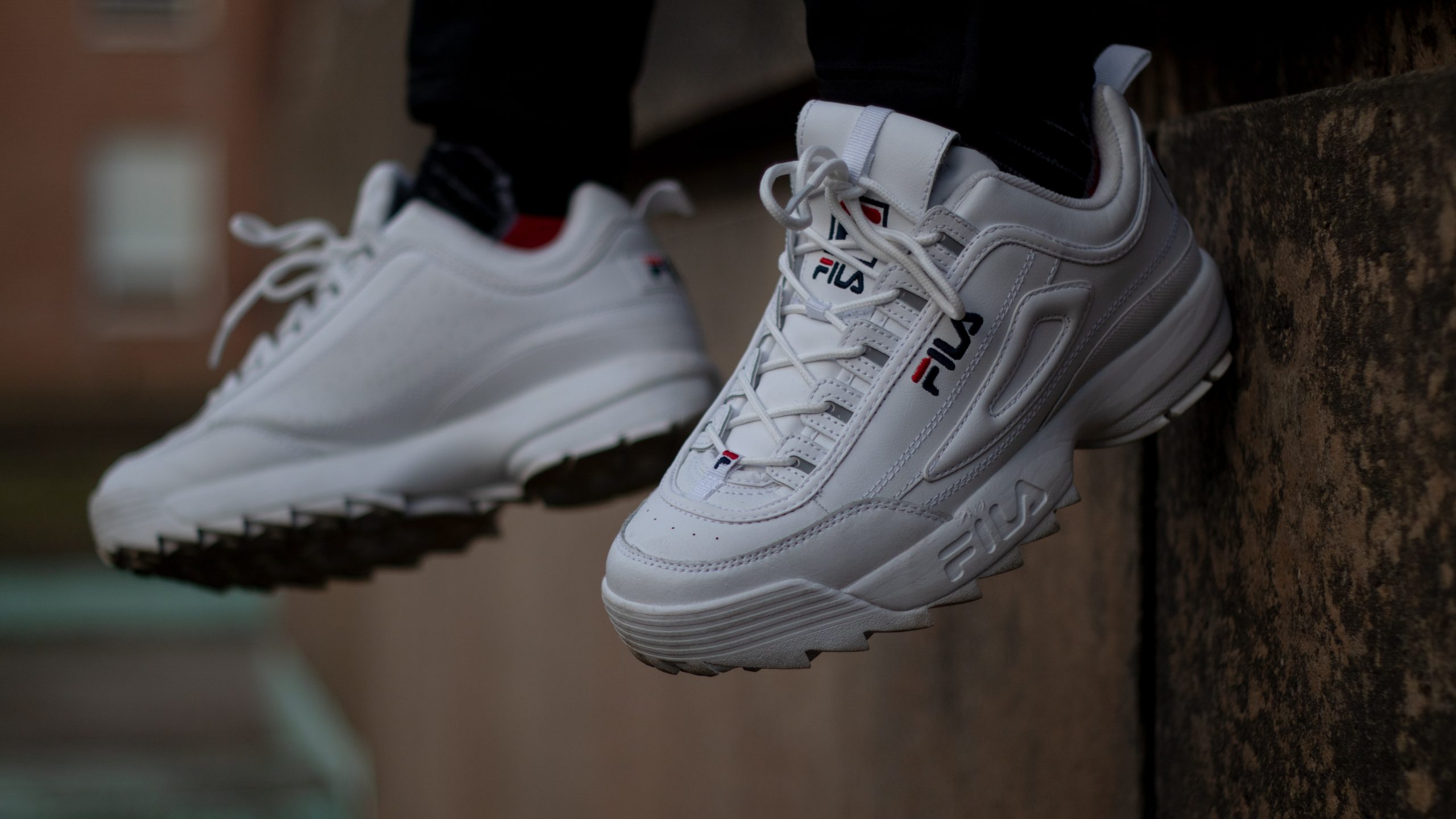 zoom sur les pieds d'une personne portant des baskets fila disruptor 2 blanches