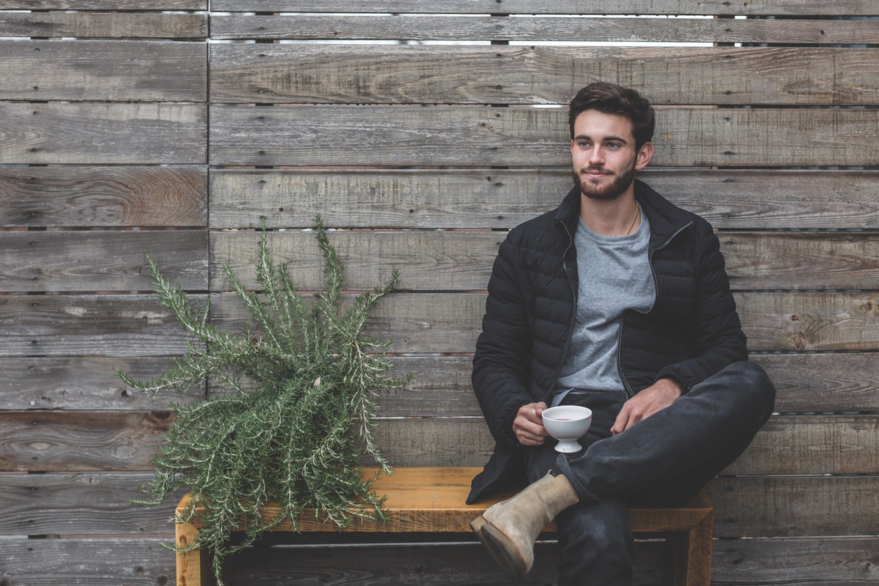 jeune homme assis sur un banc une tasse à la main